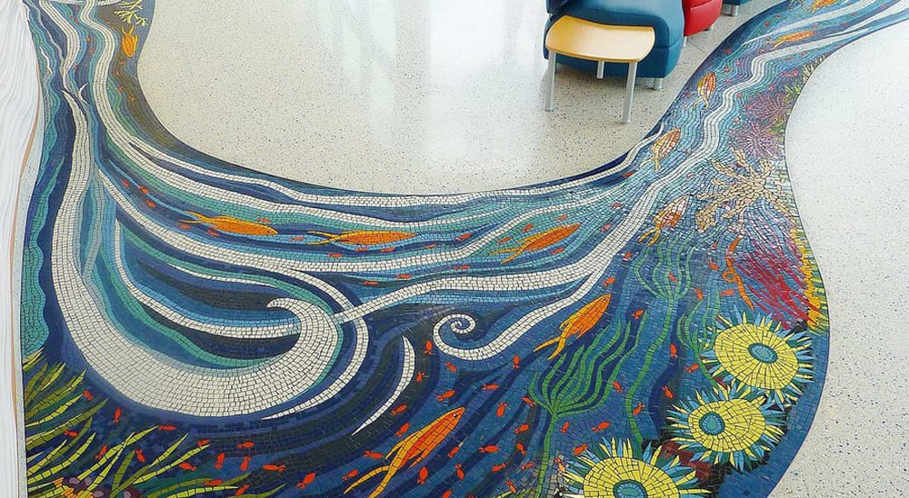 Kim Emerson’s “River of Life” mosaic moves through the main lobby of Rady Children’s Hospital, under a glass wall, and into a garden.